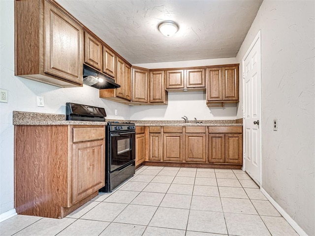 6604 NW 32nd St, Bethany, OK 73008 - kitchen featuring black gas range, under cabinet range hood, brown cabinetry, light tile patterned flooring, and light countertops