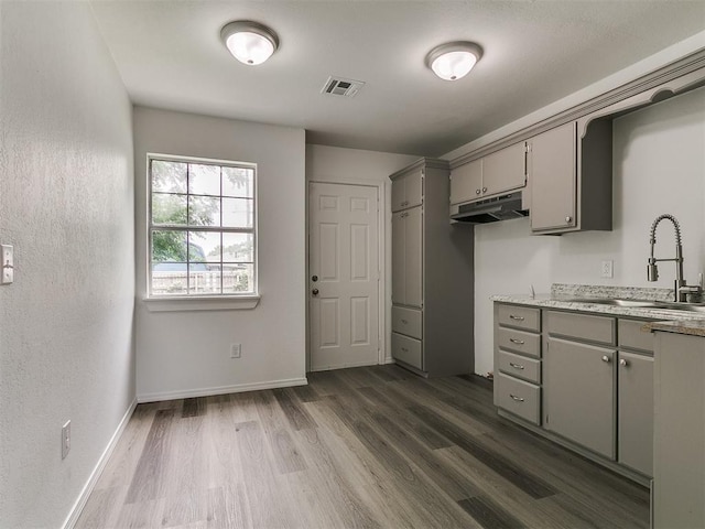 1513 Rancho Dr, Oklahoma City, OK 73119 - kitchen featuring gray cabinetry, under cabinet range hood, dark wood-style flooring, and light countertops