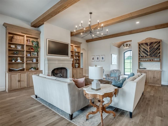 19890 Hickory Ridge Rd, Arcadia, OK 73007 - living room featuring beam ceiling, light wood-style floors, a chandelier, a fireplace, and arched walkways