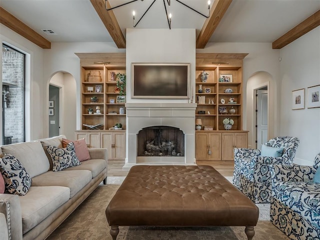 19890 Hickory Ridge Rd, Arcadia, OK 73007 - living area featuring arched walkways, beam ceiling, a fireplace, light wood finished floors, and built in features