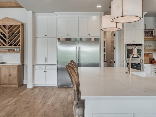 19890 Hickory Ridge Rd, Arcadia, OK 73007 - kitchen with stainless steel appliances, white cabinets, light wood-style floors, light stone countertops, and recessed lighting