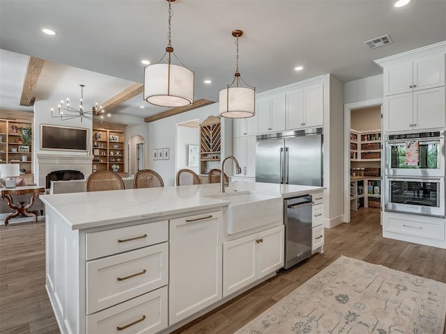 19890 Hickory Ridge Rd, Arcadia, OK 73007 - kitchen with appliances with stainless steel finishes, hanging light fixtures, beam ceiling, open floor plan, and white cabinetry
