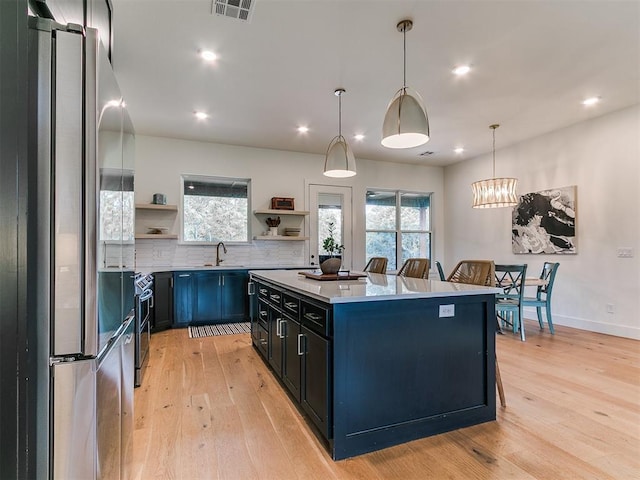 11275 S Henney Rd, Meridian, OK 73058 - kitchen with stainless steel appliances, open shelves, light wood-style flooring, a kitchen island, and decorative backsplash