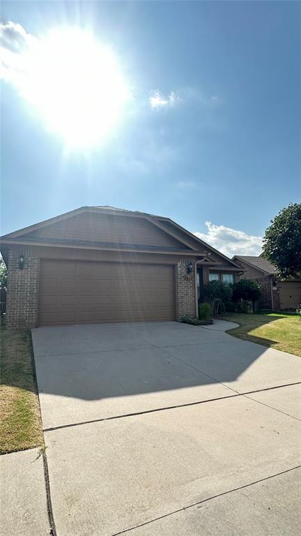 view of front of house with driveway, a garage, and brick siding