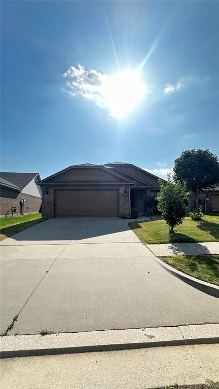 view of front of house featuring an attached garage, driveway, and a front lawn
