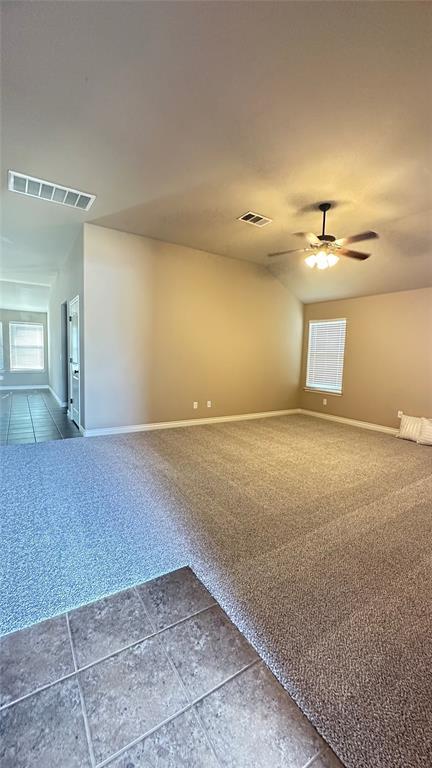 carpeted empty room featuring a ceiling fan and tile patterned flooring