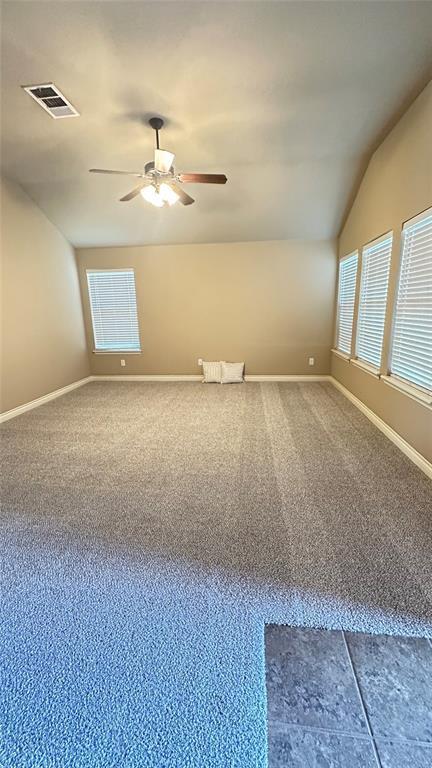 spare room with ceiling fan, vaulted ceiling, and carpet floors