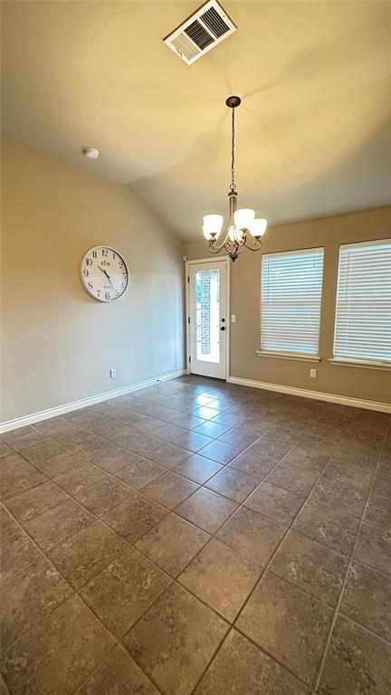 spare room with dark tile patterned flooring, a chandelier, and lofted ceiling