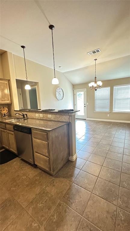 kitchen with stainless steel dishwasher, dark tile patterned floors, a chandelier, a peninsula, and pendant lighting