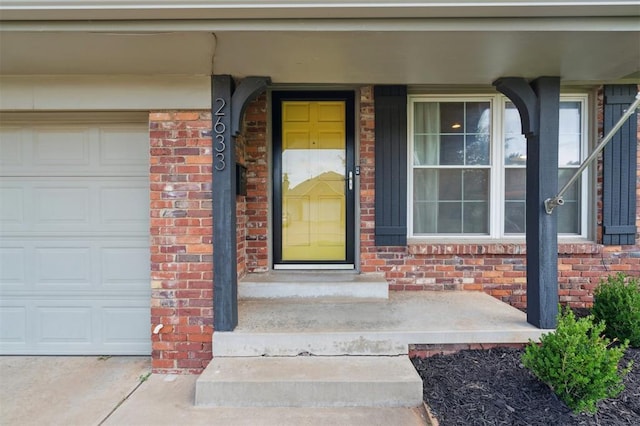 2633 Chaucer Dr, The Village, OK 73120 - view of exterior entry featuring brick siding, a garage, and covered porch