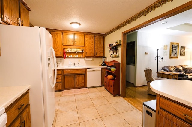 207 S Mcclure Ave, Pauls Valley, OK 73075 - kitchen with white appliances, brown cabinetry, light countertops, a textured ceiling, and open floor plan
