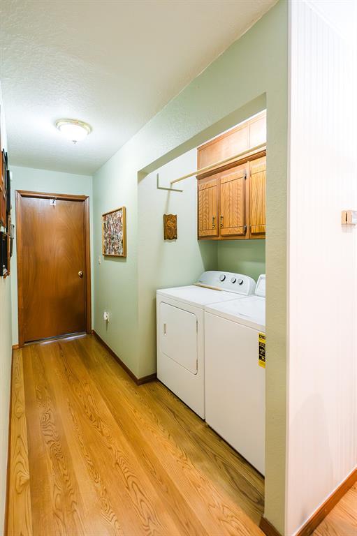 207 S Mcclure Ave, Pauls Valley, OK 73075 - washroom featuring cabinet space, washer and dryer, and light wood finished floors