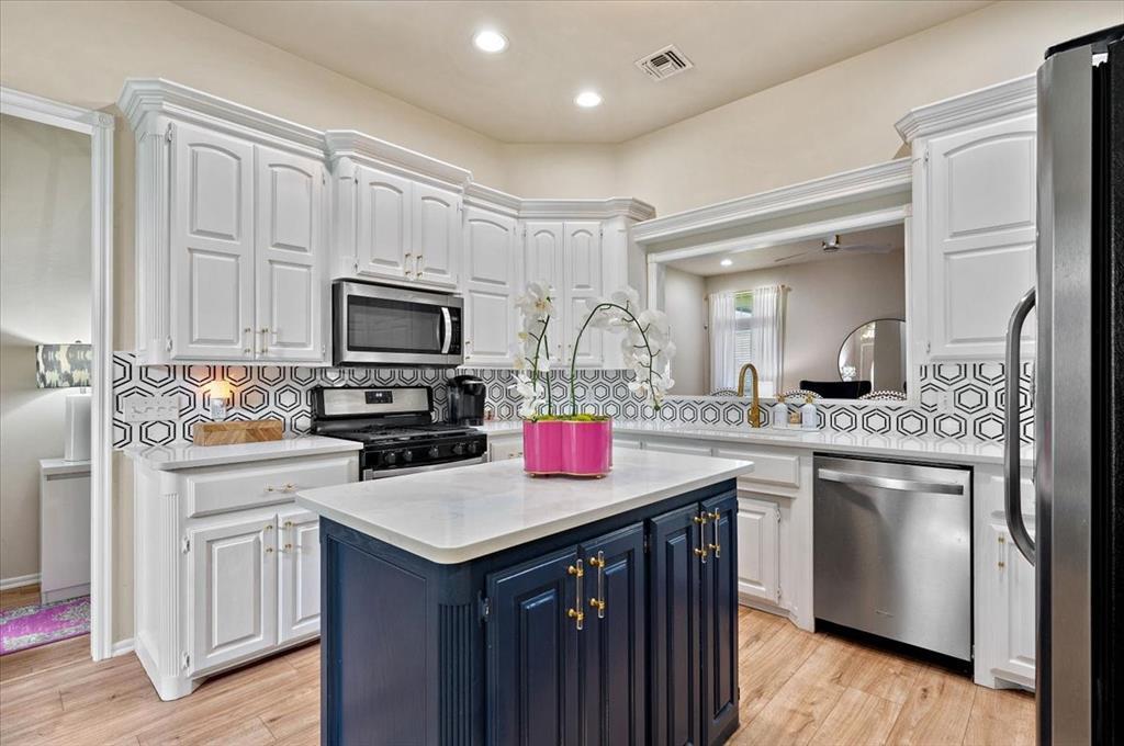 1318 Locust Dr, Blanchard, OK 73010 - kitchen with appliances with stainless steel finishes, white cabinets, light countertops, a center island, and blue cabinetry
