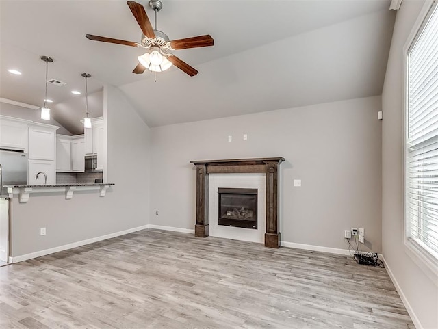 8612 SW 36th Ter, Oklahoma City, OK 73179 - unfurnished living room featuring lofted ceiling, a ceiling fan, a glass covered fireplace, and light wood finished floors