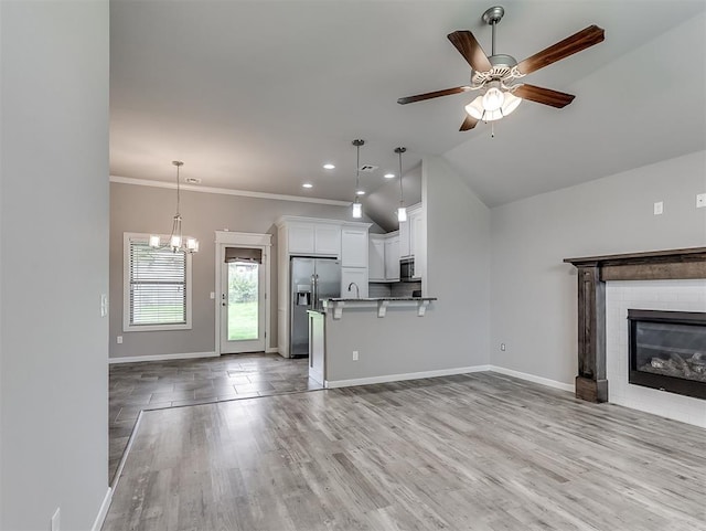 8612 SW 36th Ter, Oklahoma City, OK 73179 - unfurnished living room with a ceiling fan, a fireplace, a chandelier, light wood-type flooring, and recessed lighting