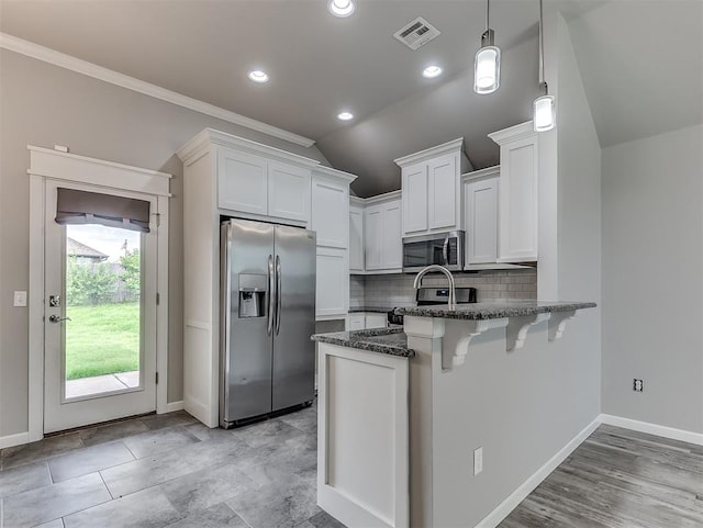 8612 SW 36th Ter, Oklahoma City, OK 73179 - kitchen with appliances with stainless steel finishes, a peninsula, dark stone countertops, white cabinetry, and tasteful backsplash