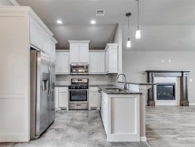 8612 SW 36th Ter, Oklahoma City, OK 73179 - kitchen featuring appliances with stainless steel finishes, a peninsula, tasteful backsplash, dark stone counters, and white cabinetry