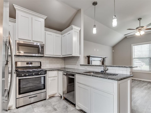 8612 SW 36th Ter, Oklahoma City, OK 73179 - kitchen featuring appliances with stainless steel finishes, lofted ceiling, decorative backsplash, a peninsula, and white cabinetry