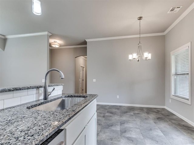8612 SW 36th Ter, Oklahoma City, OK 73179 - kitchen featuring ornamental molding, white cabinetry, arched walkways, light stone countertops, and decorative light fixtures