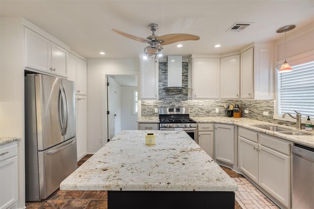 615 NW 26th St, Oklahoma City, OK 73103 - kitchen with stainless steel appliances, wall chimney range hood, tasteful backsplash, ceiling fan, and white cabinets