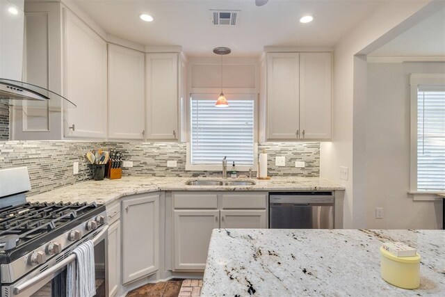 615 NW 26th St, Oklahoma City, OK 73103 - kitchen featuring stainless steel appliances, wall chimney range hood, white cabinetry, decorative backsplash, and recessed lighting