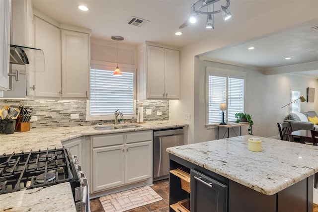 615 NW 26th St, Oklahoma City, OK 73103 - kitchen featuring stainless steel appliances, decorative backsplash, white cabinets, light stone countertops, and decorative light fixtures