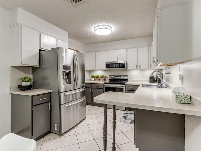 501 E Cardinal Pl, Midwest City, OK 73130 - kitchen featuring stainless steel appliances, light countertops, a textured ceiling, white cabinets, and light tile patterned flooring