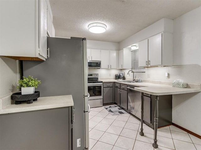 501 E Cardinal Pl, Midwest City, OK 73130 - kitchen featuring stainless steel appliances, a textured ceiling, white cabinets, light countertops, and gray cabinets