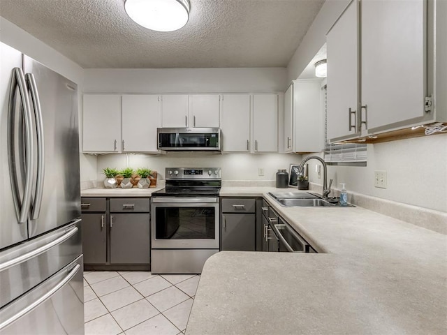 501 E Cardinal Pl, Midwest City, OK 73130 - kitchen with appliances with stainless steel finishes, a textured ceiling, light countertops, white cabinets, and light tile patterned floors