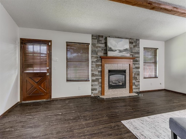 501 E Cardinal Pl, Midwest City, OK 73130 - unfurnished living room with wood finished floors, plenty of natural light, a textured ceiling, and a tiled fireplace