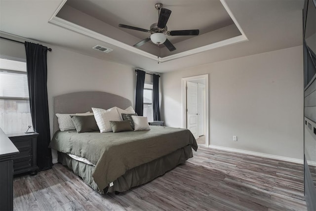 8317 Poplar Dr, Edmond, OK 73034 - bedroom with a tray ceiling, wood finished floors, and ceiling fan