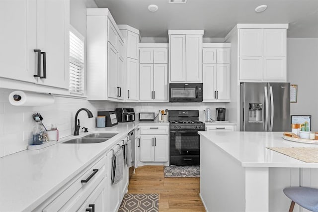 321 SW 147th St, Oklahoma City, OK 73160 - kitchen featuring black appliances, light wood-type flooring, white cabinetry, a kitchen breakfast bar, and light countertops