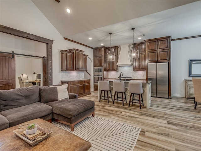 1470 Auburn Cir, Piedmont, OK 73078 - living room featuring a barn door, recessed lighting, light wood finished floors, and lofted ceiling