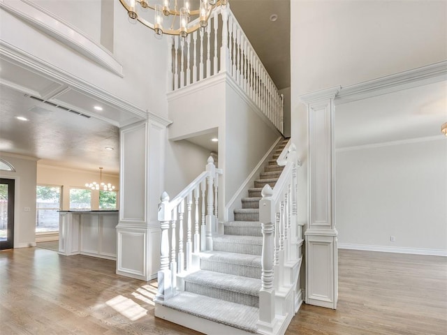 1008 Bentbrook Pl, Norman, OK 73072 - stairs with a chandelier, wood finished floors, ornamental molding, a towering ceiling, and decorative columns