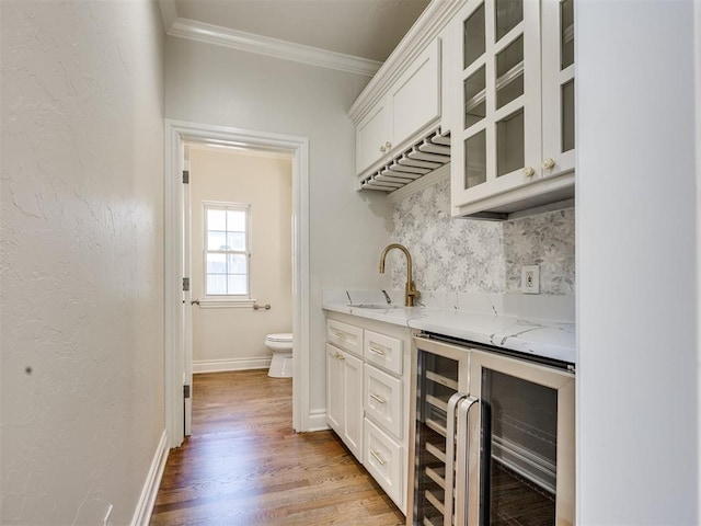 1008 Bentbrook Pl, Norman, OK 73072 - indoor wet bar featuring wine cooler, ornamental molding, light wood-style floors, and backsplash