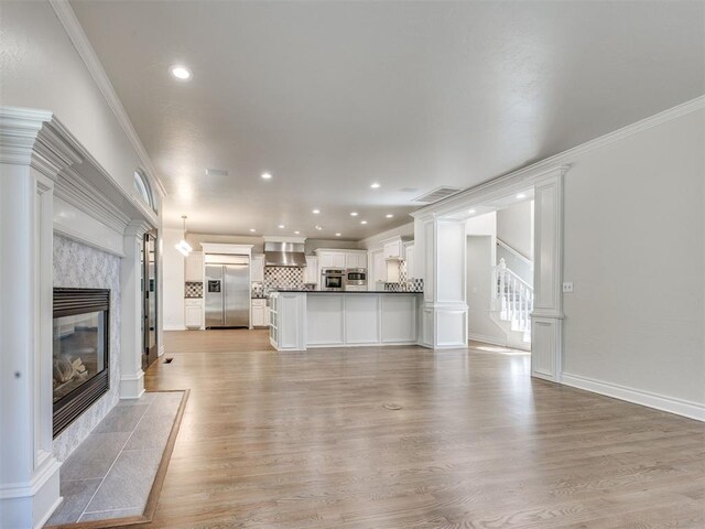 1008 Bentbrook Pl, Norman, OK 73072 - unfurnished living room featuring a high end fireplace, light wood-style flooring, ornamental molding, stairs, and recessed lighting