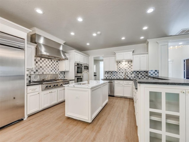 1008 Bentbrook Pl, Norman, OK 73072 - kitchen with built in appliances, wall chimney range hood, light wood-type flooring, decorative backsplash, and recessed lighting
