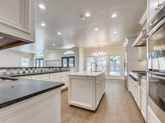 1008 Bentbrook Pl, Norman, OK 73072 - kitchen with appliances with stainless steel finishes, a chandelier, an island with sink, light wood finished floors, and recessed lighting