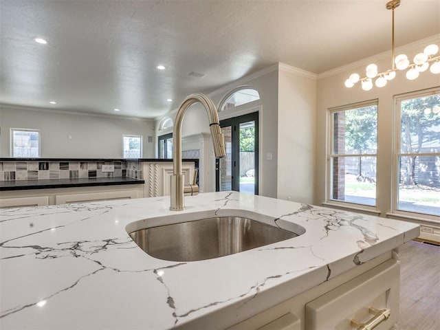 1008 Bentbrook Pl, Norman, OK 73072 - kitchen featuring light stone countertops, wood finished floors, crown molding, pendant lighting, and a fireplace