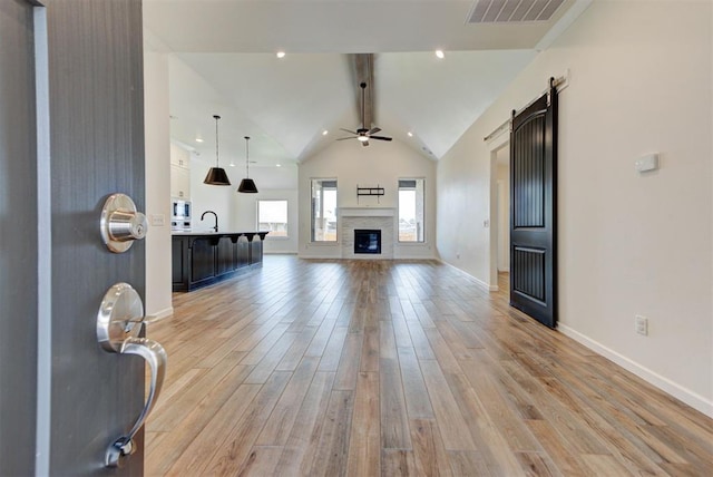 1632 NE 35th St, Moore, OK 73160 - living room with ceiling fan, vaulted ceiling, light wood finished floors, a glass covered fireplace, and a barn door