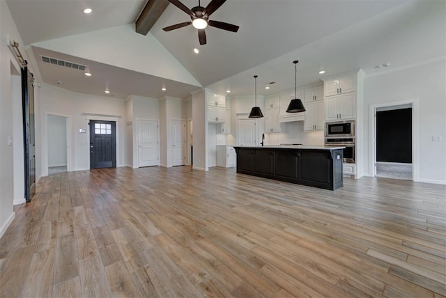 1632 NE 35th St, Moore, OK 73160 - unfurnished living room with beamed ceiling, a ceiling fan, light wood-style flooring, a barn door, and high vaulted ceiling