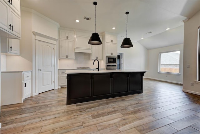 1632 NE 35th St, Moore, OK 73160 - kitchen with stainless steel appliances, light countertops, light wood-style floors, white cabinets, and vaulted ceiling