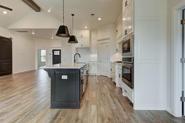 1632 NE 35th St, Moore, OK 73160 - kitchen featuring oven, white cabinets, light countertops, a center island with sink, and light wood-style flooring