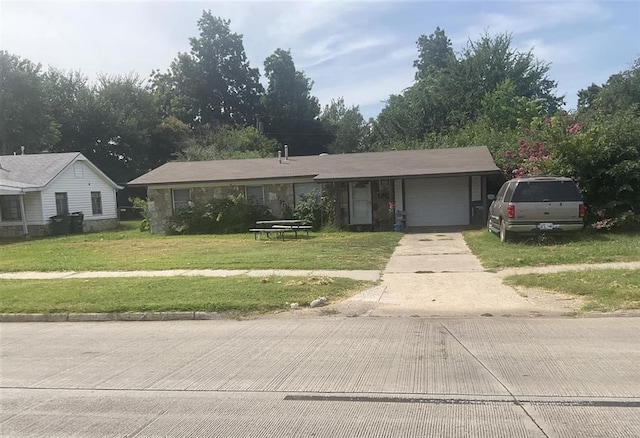 single story home featuring a garage, concrete driveway, a front yard, and stone siding