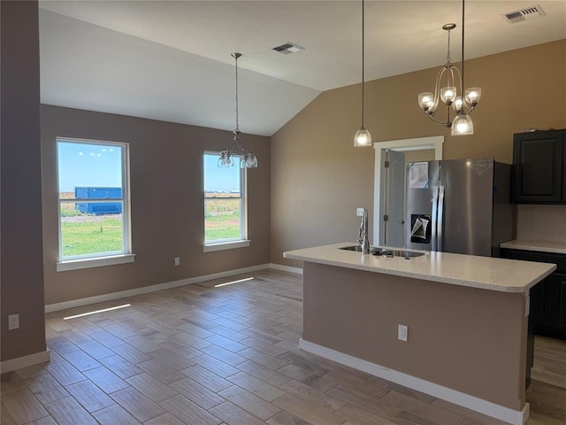 1808 Sommerset Pl, Altus, OK 73521 - kitchen with stainless steel fridge, a chandelier, vaulted ceiling, light wood-style flooring, and a kitchen island with sink