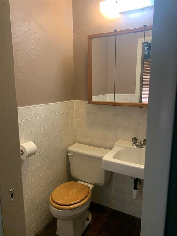 28153 County Street 2540Th, St, Fort Cobb, OK 73038 - bathroom featuring tile walls, a textured wall, a wainscoted wall, and wood finished floors