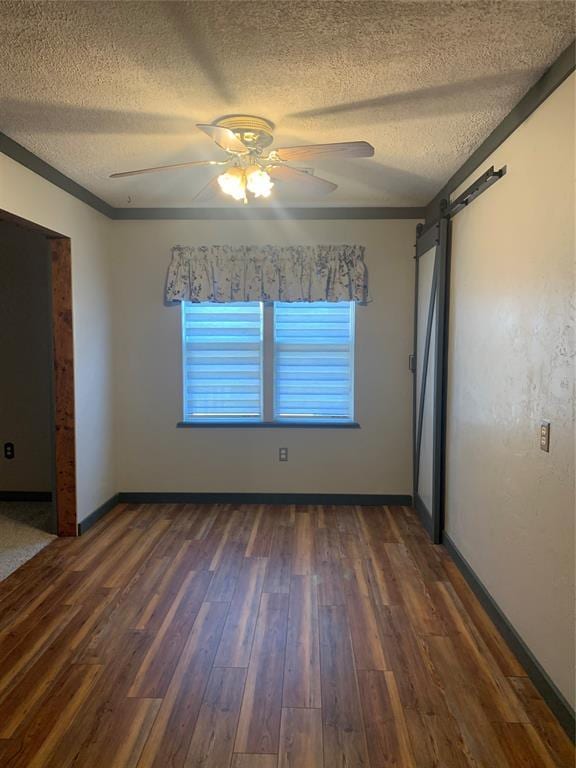 28153 County Street 2540Th, St, Fort Cobb, OK 73038 - unfurnished room with a textured ceiling, a barn door, dark wood-style floors, and ceiling fan