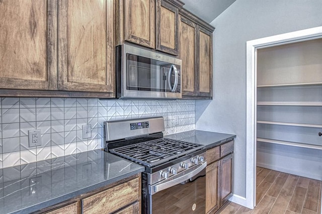 6413 SE 84th St, Oklahoma City, OK 73135 - kitchen featuring stainless steel appliances, backsplash, dark stone counters, light wood-type flooring, and vaulted ceiling