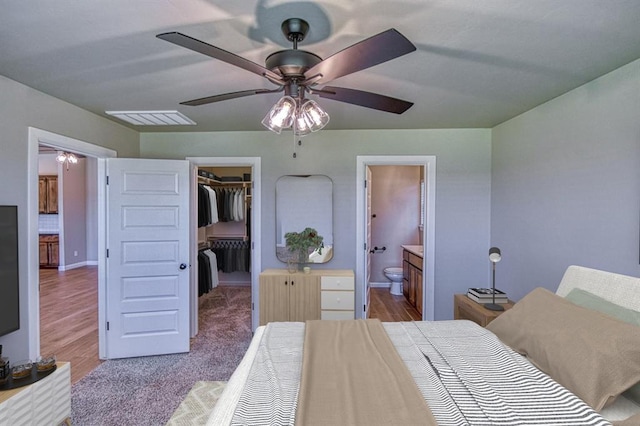 6413 SE 84th St, Oklahoma City, OK 73135 - bedroom featuring a spacious closet, ensuite bathroom, a ceiling fan, and wood finished floors