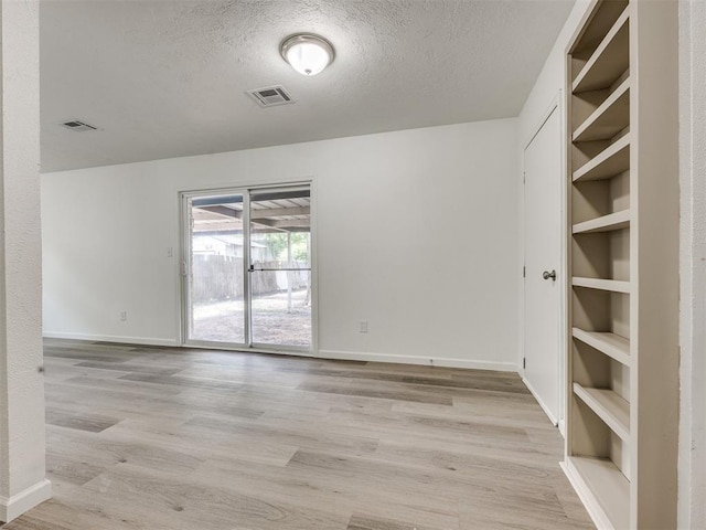 3044 S Madole Blvd, Oklahoma City, OK 73159 - empty room featuring built in features, a textured ceiling, and light wood-style flooring